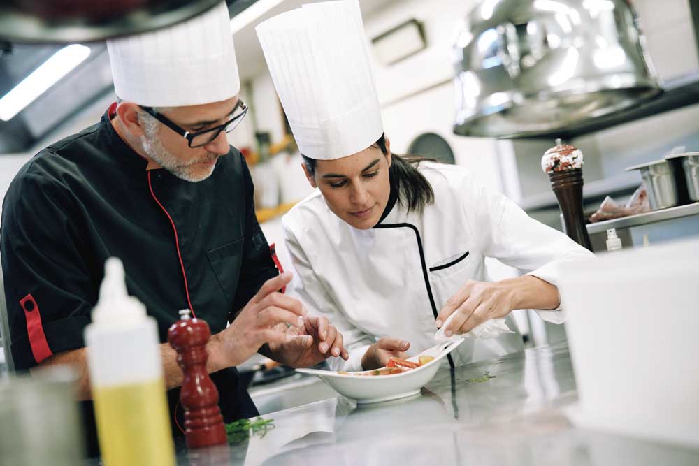 Eine Prise Theorie, eine Messerspitze Praxis - Ausbildung und Karriere - Professional cook chefs in kitchen improving dish composition