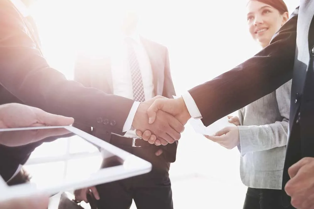 Rechtsformwahl im Zuge einer Betriebsübergabe im Familienverband - Ausbildung und Karriere - employees look at the handshake business partners jpg