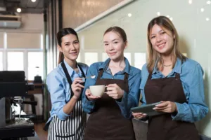 Startseite - Ausbildung und Karriere - Group of young women barista working and preparing coffee for customer in coffee shop. Coffee owner concept. Small business and start up business