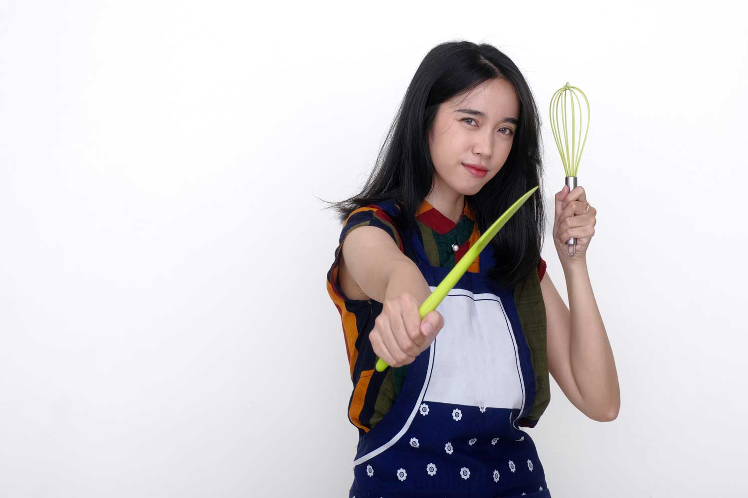 Praktika suchen und finden - Ausbildung und Karriere - A young woman wearing an apron holds a spatula and a whisk in a serious